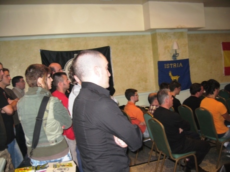 Al final de la sala, tanto a derecha como a izquierda, los asistentes en pie escuchan las conferencias.
